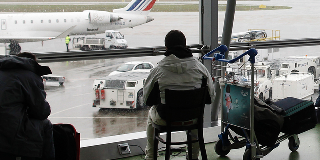 FILE - In this Dec.17, 2011 file photo, a passenger waits for his flight during a strike at Lyon-Saint Exupery airport, central France. Authorities say police have arrested a man who rammed his car through two glass doors at Lyon's international airport and sped onto the runway. (AP Photo/Laurent Cipriani, File)