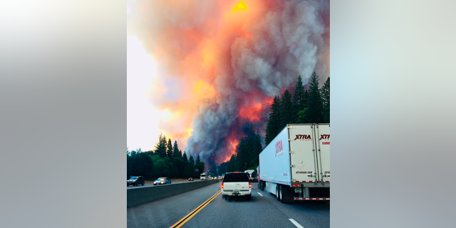 A fire rages as motorists travel on Interstate 5 near Lake Shasta, Calif., Wednesday, Sept. 5, 2018. (Jerri Tubbs via AP)