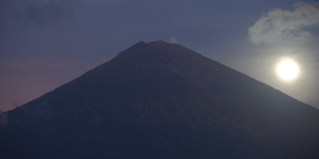 A full moon is set behind the Mount Agung volcano in Karangasem, Bali, Indonesia, Friday, Oct. 6, 2017.