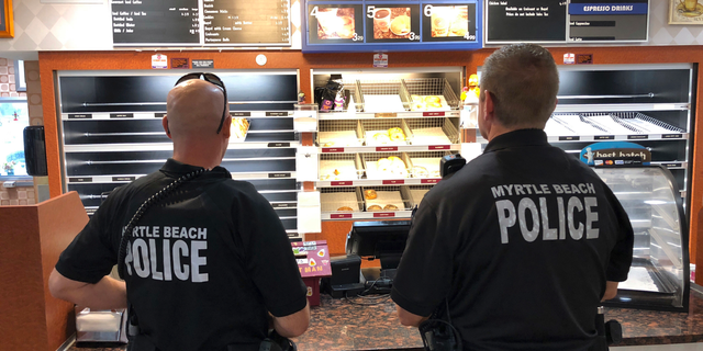 Two police officers get ready to order at Joseph Santos' Donut Man restaurant in Myrtle Beach, S.C., on Friday, Sept. 14, 2018. Santos says he keeps his restaurant open to feed police officers, firefighters and others who have to work no matter what. (AP Photo/Jeffrey Collins)