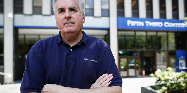 In this Friday, Sept. 14, 2018 photo, Associated Press senior correspondent Dan Sewell poses for a photograph outside the scene of a shooting that occurred the previous week at Fountain Square, in Cincinnati. "Over four decades with The Associated Press, I have many times thrown clothes into a bag, withdrawn a wad of cash, and stuffed my laptop with notebooks and pens before rushing by car or plane to a terrible event in someone else's hometown, state or country," said Sewell. "This time, it was in my town." (AP Photo/John Minchillo)
