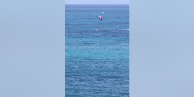 A kite surfer rides a wave as Tropical Storm Olivia approaches Hawaii, Tuesday, Sept. 11, 2018, near Honolulu. The National Weather Service says the storm could dump as much as 20 inches of rain on some parts of the islands as it hits late Tuesday and into Wednesday. (AP Photo/Caleb Jones)