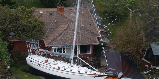 A sailboat is shoved up against a house and a collapsed garage Saturday, Sept. 15, 2018, after heavy wind and rain from Florence, now a tropical storm, blew through New Bern, N.C. (AP Photo/Steve Helber)