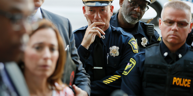 Members of the Cincinnati Police Department listen as Chief Eliot Isaac speaks to the media as emergency personnel and police work the scene of a shooting near Fountain Square, Thursday, Sept. 6, 2018, in downtown Cincinnati. (AP Photo/John Minchillo)