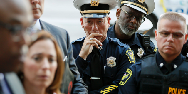 Members of the Cincinnati Police Department listen as Chief Eliot Isaac speaks to the media as emergency personnel and police work the scene of a shooting near Fountain Square, Thursday, Sept. 6, 2018, in downtown Cincinnati. (AP Photo/John Minchillo)