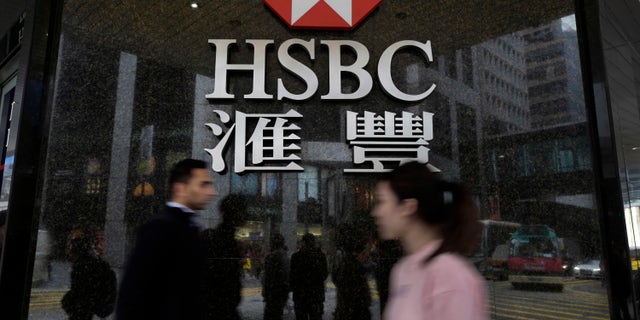 FILE - In this Feb. 21, 2017 file photo, people walk past a branch of HSBC bank in Hong Kong. HSBC says quarterly pretax profits rose 12 percent as improved trading and rising interest rates helped support the London-based global bank’s businesses. The bank said on Thursday, May 4, that profit for the first three months of the year, adjusted for one-time items and currency fluctuations, came in at $5.9 billion versus $5.3 billion a year ago. Adjusted revenue edged 2 percent higher to $12.8 billion. (AP Photo/Vincent Yu, File)