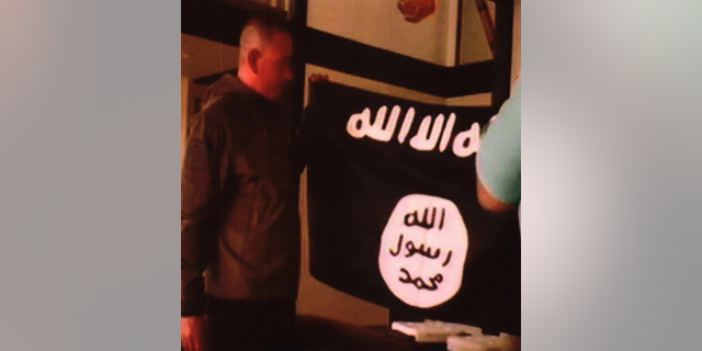 Army Sgt. 1st Class Ikaika Kang holds an ISIS flag after allegedly pledging allegiance to the group at a house in Honolulu on July 8.