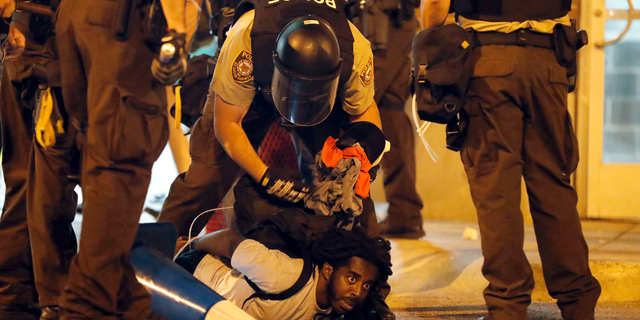 FILE - In this Sept. 17, 2017, file photo, police arrest a man as demonstrators march in response to a not guilty verdict in the trial of former St. Louis police officer Jason Stockley in St. Louis. Stockley was acquitted in the 2011 killing of a black man following a high-speed chase. More than a dozen people arrested in the 2017 protest in St. Louis are suing the city, police officers and their supervisors, alleging they were roughed up, pepper sprayed and illegally detained. Federal lawsuits were filed Monday, Sept. 17, 2018, a year to the day after the downtown protest. (AP Photo/Jeff Roberson, File)