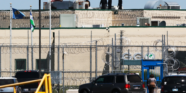 People walk on the roof above the front gate of the Great Plains Correctional Facility in Hinton, Okla, Monday, July 10, 2017.