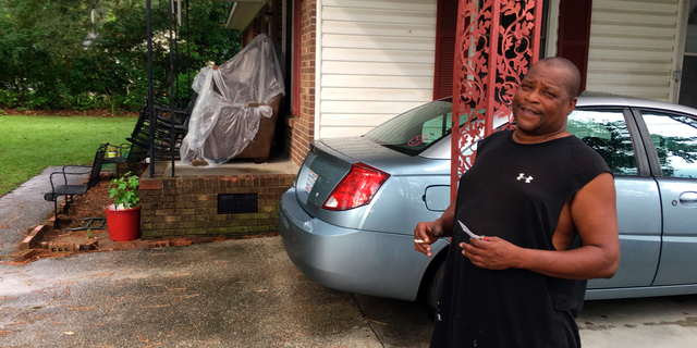 James Howell Jr. sizes up how to protect his home Tuesday, Sept. 11, 2018, in Princeville, N. C., from the approaching Hurricane Florence. The house was damaged by Hurricane Matthew in 2016. Howell said the furniture on his porch is there because he had to go out and rebuild the living room. (AP Photo/Emery Dalesio)