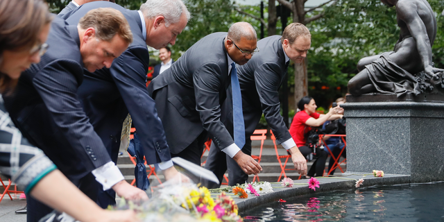 Mourners place flowers at the fountain edge before a vigil in Fountain Square where a shooting took place the previous day that claimed the lives of three civilians, Friday, Sept. 7, 2018, in Cincinnati. Suspect Omar Enrique Santa Perez entered the Fifth Third Center and began firing before being neutralized by police officers. (AP Photo/John Minchillo)