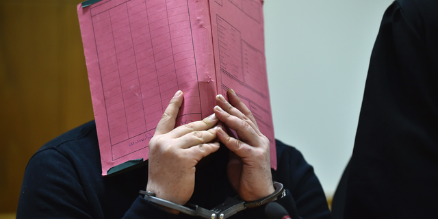 Niels Hoegel covering his face during his trial at the regional court in in Oldenburg, northern Germany, in 2015.