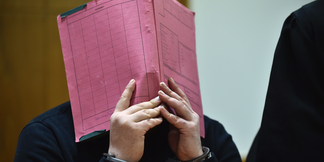 Niels Hoegel covering his face during his trial at the regional court in in Oldenburg, northern Germany, in 2015.