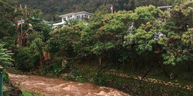Water rushes through a spillway in a neighborhood below the Nuuanu Dam in Honolulu on Thursday, Sept. 13, 2018. Honolulu officials say they may need to evacuate 10,000 people from a residential neighborhood if water in the reservoir continues to rise after heavy rains from a tropical storm. (AP Photo/Caleb Jones)