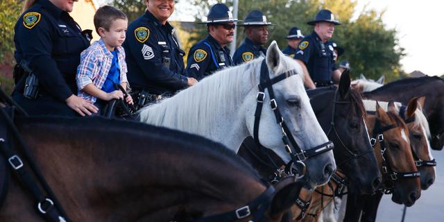 Kevin Will Jr., 5, the son of slain Houston police officer Kevin Will, sits on top of a horse as he is escorted to his first day of school by Houston police and other officers Tuesday, Aug. 22, 2017 in Cypress, Texas.