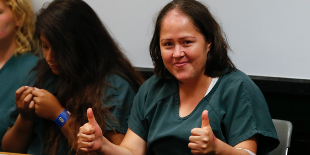 Isabel Martinez, the woman accused of fatally stabbing her four children and husband, smiles and gives two thumbs up at her court hearing.