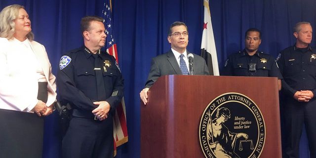 California Attorney General, Xavier Becerra, at podium, and other officials announce indictments of 32 members of purported street gangs on charges of stealing more than $1 million using an unusually sophisticated credit card fraud, at a news conference in Sacramento, Calif., Monday, Sept. 10, 2018. From left are Deputy Attorney General Tawnya Austin, who heads the attorney general's e-crimes unit; Walnut Creek Police Chief Tom Chaplin; Becerra; Sacramento Police Chief Daniel Hahn; and Vacaville Police Chief John Carli. Authorities said Monday that the BullyBoys and the CoCo Boys street gangs defrauded hundreds of victims across Northern California by breaking into dozens of medical and dental offices to steal credit card terminals and patient records. (AP Photo/Don Thompson)