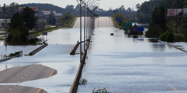 FILE- In this Monday, Sept. 17, 2018, file photo flooded vehicles sit on a closed section of Interstate 95 in Lumberton, N.C., where the Lumber river overflowed following flooding from Hurricane Florence. Navigation apps like Waze are trying to help motorists avoid hurricane flooding, but local authorities say people shouldn’t rely on them. (AP Photo/Gerry Broome, File)