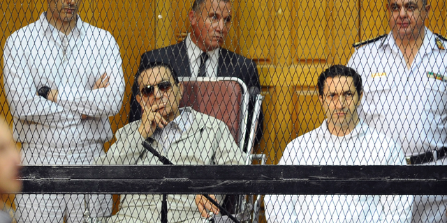 FILE - In this Sept. 14, 2013 file photo, former Egyptian President Hosni Mubarak, seated center left, and his two sons, Gamal Mubarak, left, and Alaa Mubarak attend a hearing in a courtroom in Cairo, Egypt. Egyptian officials say police have detained the sons of former president Hosni Mubarak in connection with inside trading charges. They said the arrests were ordered Saturday, Sept. 15, 2018 by judge Ahmed Aboul-Fetouh before he adjourned the hearings to October 20. (AP Photo/Mohammed al-Law, File)