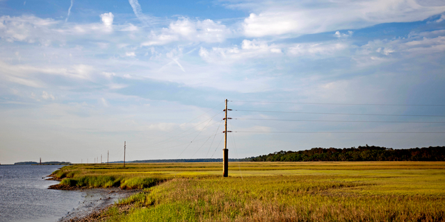 FILE - In this May 16, 2013, file photo, a utility pole stands in the middle of a marsh at sunset on Sapelo Island, Ga., a Gullah-Geechee community. A tight-knit community of slave descendants on the South Carolina coast is used to riding out big storms, from a storm that killed an estimated 2,000 people in 1893 to Tropical Storm Irma last year. (AP Photo/David Goldman, File)