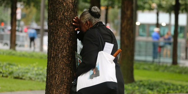 A woman weeps by herself as she leans against a tree during a ceremony marking the 17th anniversary of the terrorist attacks on the United States. Tuesday, Sept. 11, 2018, at the World Trade Center in New York. (AP Photo/Mark Lennihan)