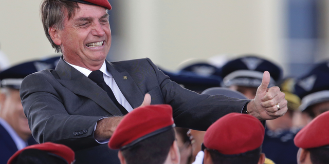 FILE - In this April 19, 2018 file photo, presidential hopeful, conservative Brazilian lawmaker Jair Bolsonaro flashes two thumbs up as he poses for a photo with cadets during a ceremony marking Army Day, in Brasilia, Brazil. Bolsonaro, the leading candidate in Brazil's presidential race was discharged from the hospital Saturday, Sept. 29, 2018, where he was being treated for a knife wound to his abdomen. (AP Photo/Eraldo Peres, File)