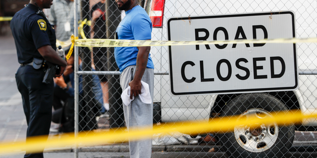 Pedestrians stand behind a police line as emergency personnel and police respond to reports of a shooting near Fountain Square, Thursday, Sept. 6, 2018, in downtown Cincinnati. (AP Photo/John Minchillo)