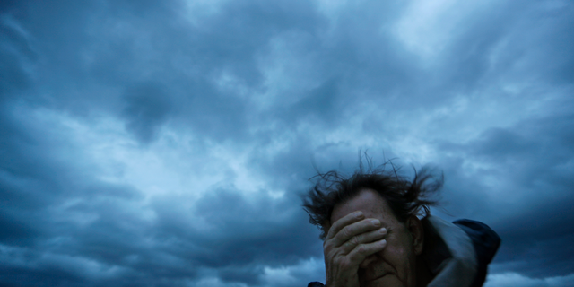 Russ Lewis covers his eyes from a gust of wind and a blast of sand as Hurricane Florence approaches Myrtle Beach, S.C., Friday, Sept. 14, 2018. (AP Photo/David Goldman)