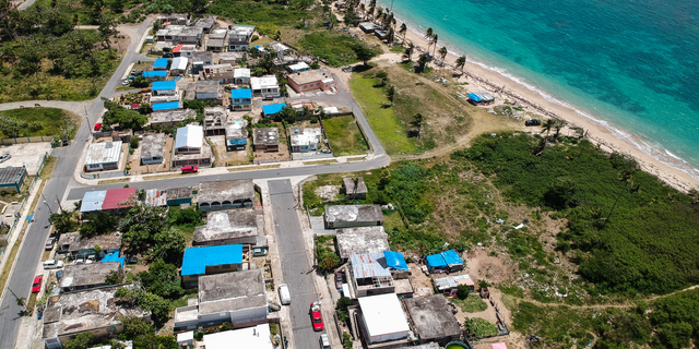 FILE - This June 18, 2018 file photo shows an aerial photo of the Viequez neighborhood, east of San Juan, Puerto Rico, where people were still living in damaged homes, protected by blue plastic tarps, nine months since Hurricane Maria devastated the island. Puerto Rico's governor said on Tuesday, Sept. 11, 2018 that his administration has adopted new measures to better prepare for a disaster like Maria while he warned of limitations given the U.S. territory's economic crisis. (AP Photo/Dennis M. Rivera, File)