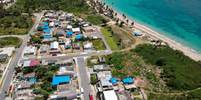 FILE - This June 18, 2018 file photo shows an aerial photo of the Viequez neighborhood, east of San Juan, Puerto Rico, where people were still living in damaged homes, protected by blue plastic tarps, nine months since Hurricane Maria devastated the island. Puerto Rico's governor said on Tuesday, Sept. 11, 2018 that his administration has adopted new measures to better prepare for a disaster like Maria while he warned of limitations given the U.S. territory's economic crisis. (AP Photo/Dennis M. Rivera, File)