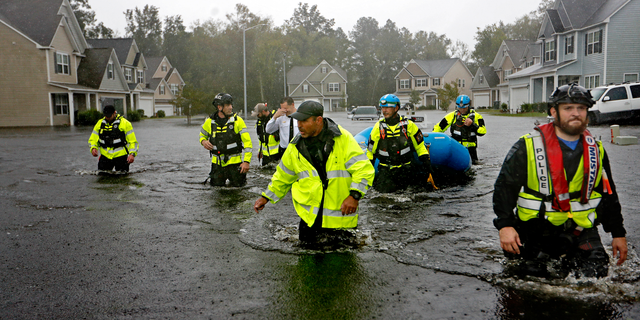 Members of the North Carolina Task Force urban search and rescue team wade through a flooded neighborhood looking for residents who stayed behind as Florence continues to dump heavy rain in Fayetteville, N.C., Sunday, Sept. 16, 2018. (AP Photo/David Goldman)