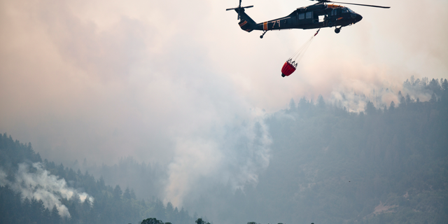 This photo taken Aug. 6, 2018, shows a helicopters returning from performing an air operation on the Coal Hollow Fire near U.S. Highway 6. An Idaho prisoner sent to help fight a wildfire in Utah raped a woman who also was working to support firefighters, prosecutors said Tuesday, Sept. 4, 2018. The woman had rejected several advances from Ruben Hernandez, 27, in the days before the Aug. 29 assault at the base camp, Sanpete County attorney Kevin Daniels said. Hernandez has been charged with felony rape. (Evan Cobb/The Daily Herald via AP)