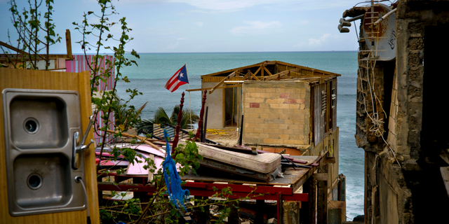 In this Oct. 5, 2017 file photo, a Puerto Rican national flag is mounted on debris of a damaged home in the aftermath of Hurricane Maria in the seaside slum La Perla, San Juan, Puerto Rico.