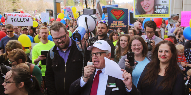 FILE - In this March 30, 2018, file photo, Sam Young, center, speaks to a group of people during a march to church headquarters, in Salt Lake City. Young, a Mormon who has led a campaign criticizing the church's practice of allowing closed-door, one-on-one interviews of youth by lay leaders, will have to wait to find out if he'll be kicked out of the religion. Young said late Sunday, Sept. 9, 2018, that local church leaders didn't make a decision following a disciplinary council at his congregation in Houston. Young says they didn't say when they will decide. (AP Photo/Rick Bowmer, File)
