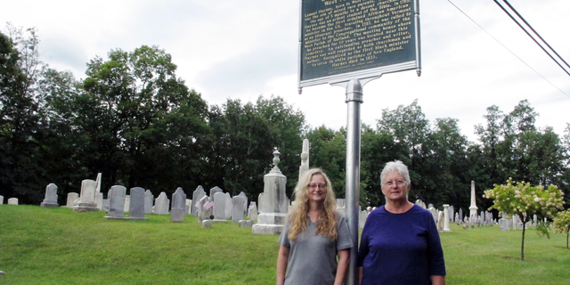 In this Sept. 6, 2018, photo, Michelle Jagodzinski, left, and Mary Reczek, right, of the West Rutland Historical Society in Vermont stand next to a new historical marker honoring Lemuel Haynes, first ordained black minister in the U.S. in West Rutland, Vt. (AP Photo/Lisa Rathke)