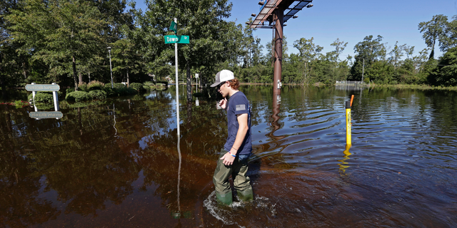 Zachary Conner wades into a flooded neighborhood to check on his girlfriend in Lumberton, N.C., Tuesday, Sept. 18, 2018, following the effects from Hurricane Florence. (AP Photo/Gerry Broome)
