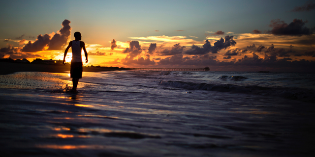 Andrew Lingle walks along the beach at sunrise as Hurricane Florence approaches the east coast in Atlantic Beach, N.C., Wednesday, Sept. 12, 2018. (AP Photo/David Goldman)