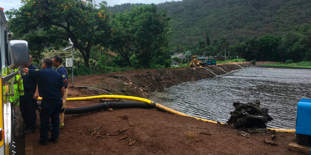 Officials pump water from a reservoir where a dam came close to overflowing in Honolulu on Thursday, Sept. 13, 2018. Honolulu officials say they may need to evacuate 10,000 people from a residential neighborhood if water in the reservoir continues to rise after heavy rains from a tropical storm. (AP Photo/Caleb Jones)