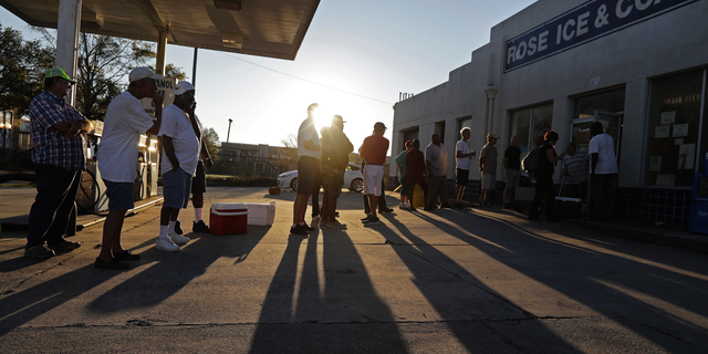 FILE - In this Sept. 19, 2018, file photo, people begin to form a line in the morning sun as they wait outside Rose Ice & Coal for it to open days after Hurricane Florence in Wilmington, N.C. Many in Wilmington woke up Wednesday suddenly very tired. The days-long scavenger hunt for gas and ice was over as stores opened and relief agencies were able to roll into the city. (AP Photo/Chuck Burton, File)