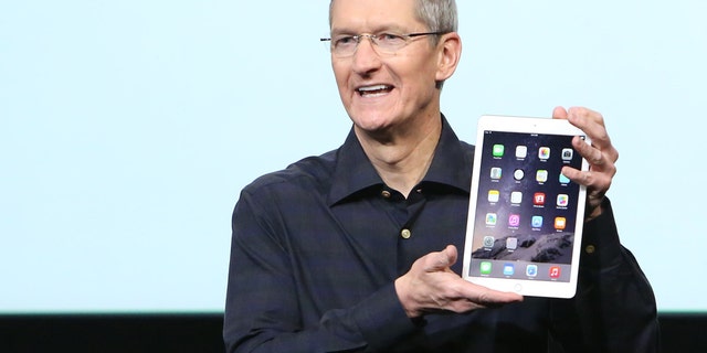 Apple CEO Tim Cook holds an iPad during a presentation at Apple headquarters October 16, 2014.