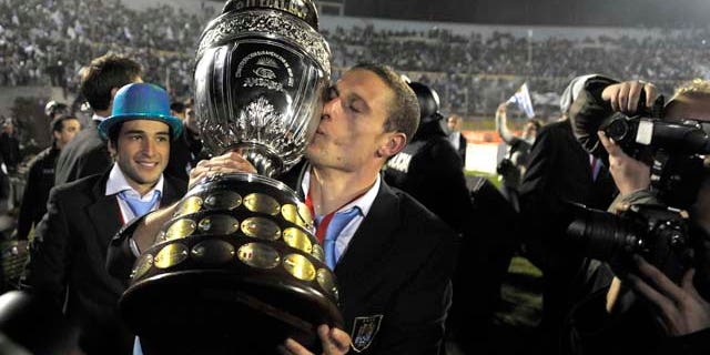 Uruguay's Diego Perez kisses the trophy as the team celebrates in the Centenario Stadium in Montevideo, Uruguay Monday July 25, 2011. Uruguay won the Copa America for a record 15th time after beating Paraguay 3-0 in Argentina Sunday. (AP Photo/Andres Cuenca) (AP Photo/Matilde Campodonico)