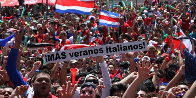 Costa Rica soccer fans celebrate after their team's World Cup victory over Italy in San Jose, Costa Rica, Friday, June 20, 2014. Costa Rica won 1-0. The sign reads in Spanish "More Italian summers!" (AP Photo/Enrique Martinez)