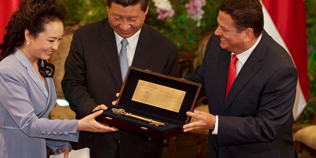 China's President Xi Jinping, center, and his wife Peng Liyuan hold the "Key to the City" given to them by San Jose Mayor Johnny Araya in San Jose, Costa Rica, Monday, June 3, 2013. After Costa Rica, Xi has planned stops in Mexico and the United States. Trinidad, a leading supplier of natural gas, was his first stop of a four-country trip in the region. (AP Photo/Arnulfo Franco)