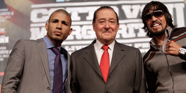 Boxers  Miguel Cotto, left,  of Puerto Rico, and  Antonio Margarito, right, of Mexico, flank promoter Bob Arum during a news conference Wednesday, Nov. 30, 2011 at Madison Square Garden in New York. Cotto will defend his WBA Super World junior middleweight title against Margarito on Saturday, Dec. 3, in New York. (AP Photo/Mary Altaffer)