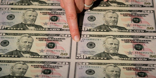 WASHINGTON - SEPTEMBER 28: Julie Borchard of the U.S. Treasury Department points out new improvements on the newly unveiled fifity dollar bill September 28, 2004 in Washington, DC. The newly redesigned bill, with a "Stars and Stripes" design theme, was released into circulation today. (Photo by Mark Wilson/Getty Images)