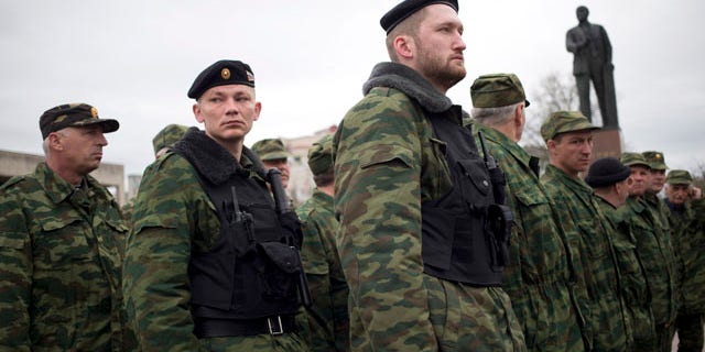 March 27, 2014: Members of the Crimean self defense forces gather for their morning briefing prior to patrolling the city at Soviet Union founder Vladimir Lenin's statue in Simferopol, Crimea. Crimea's government has decided to disband self-defense forces which provided help to the Russian military which have been occupying since late February. (AP Photo/Pavel Golovkin)