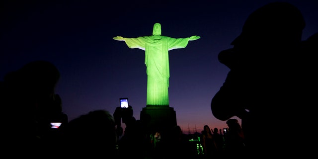 Christ the Redeemer statue is illuminated in green and yellow, the colors of the Brazil's flag, to celebrate the Summer Olympic Games, in Rio de Janeiro, Brazil, Thursday, Aug. 4, 2016. (AP Photo/Joao Laet)