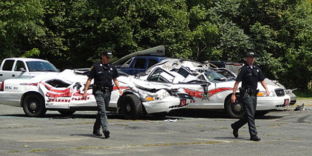 Aug. 2, 2012: Sheriff officers walk past crushed cruisers at the Orleans County Sheriff's Department in Newport, Vt.