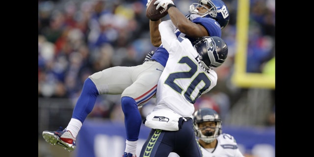 New York Giants wide receiver Victor Cruz, left, makes a catch as Seattle Seahawks cornerback Jeremy Lane defends on the play during the second half of an NFL football game, Sunday, Dec. 15, 2013, in East Rutherford, N.J. Cruz was banged up on the play and left the game with an injury. (AP Photo/Kathy Willens)
