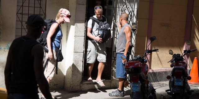 Tourist leave a privately owned home with rooms for rent in Havana, Cuba, Wednesday, April 1, 2015. The wildly popular online home-sharing service Airbnb will allow American travelers to book lodging in Cuba starting Thursday in the most significant U.S. business expansion on the island since the declaration of detente between the two countries late last year. (AP Photo/Desmond Boylan)